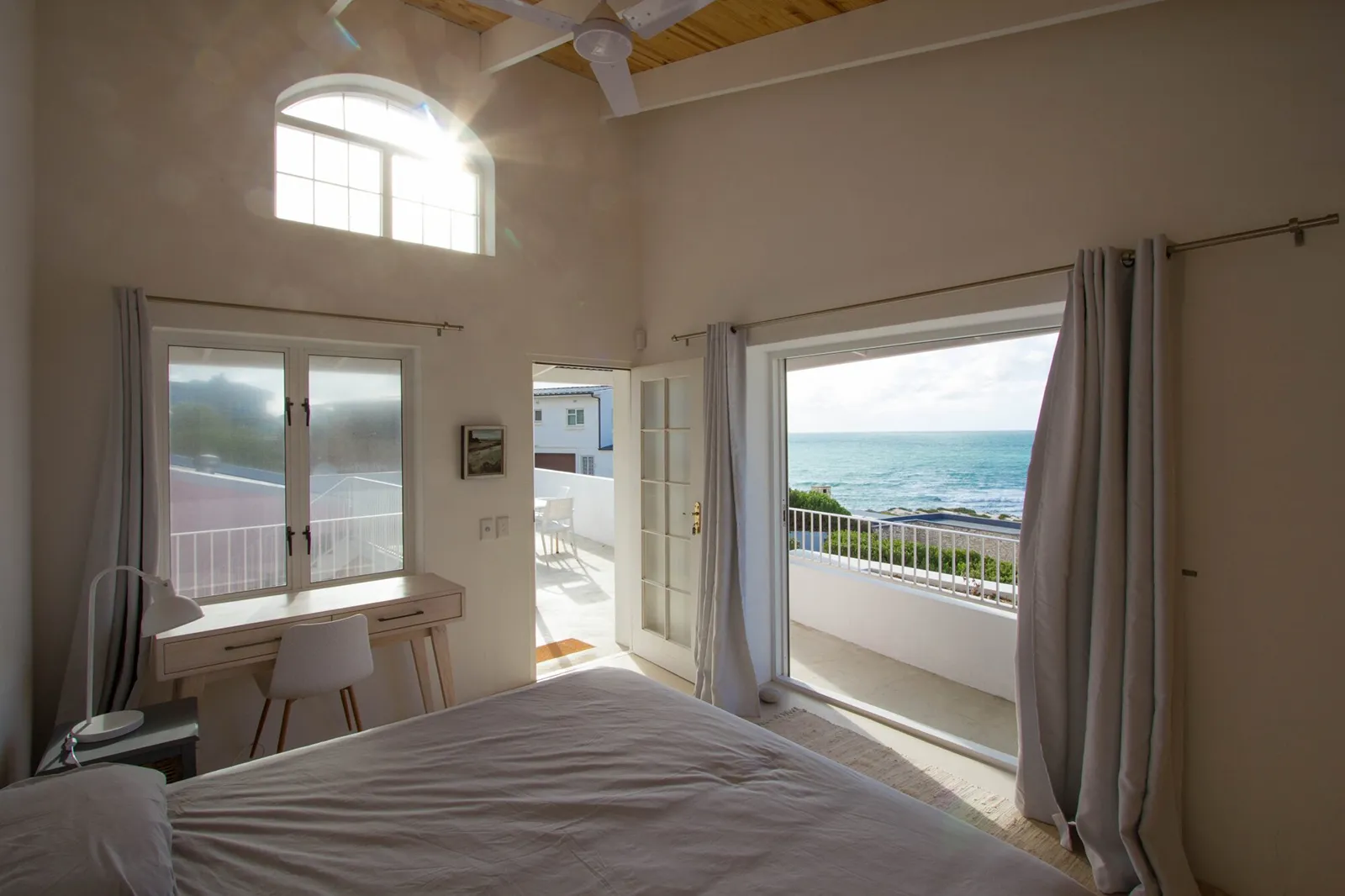 Bedroom with a double-volume window and a door opening onto a sea-view balcony