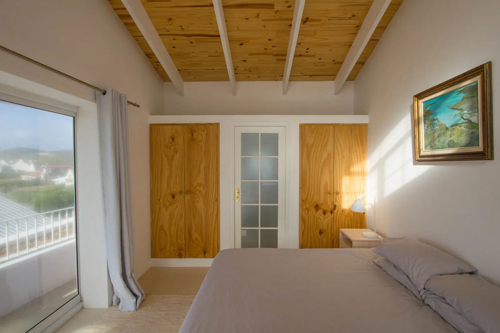 Bedroom with timber doors, a timber-beamed ceiling and a sliding door to the balcony