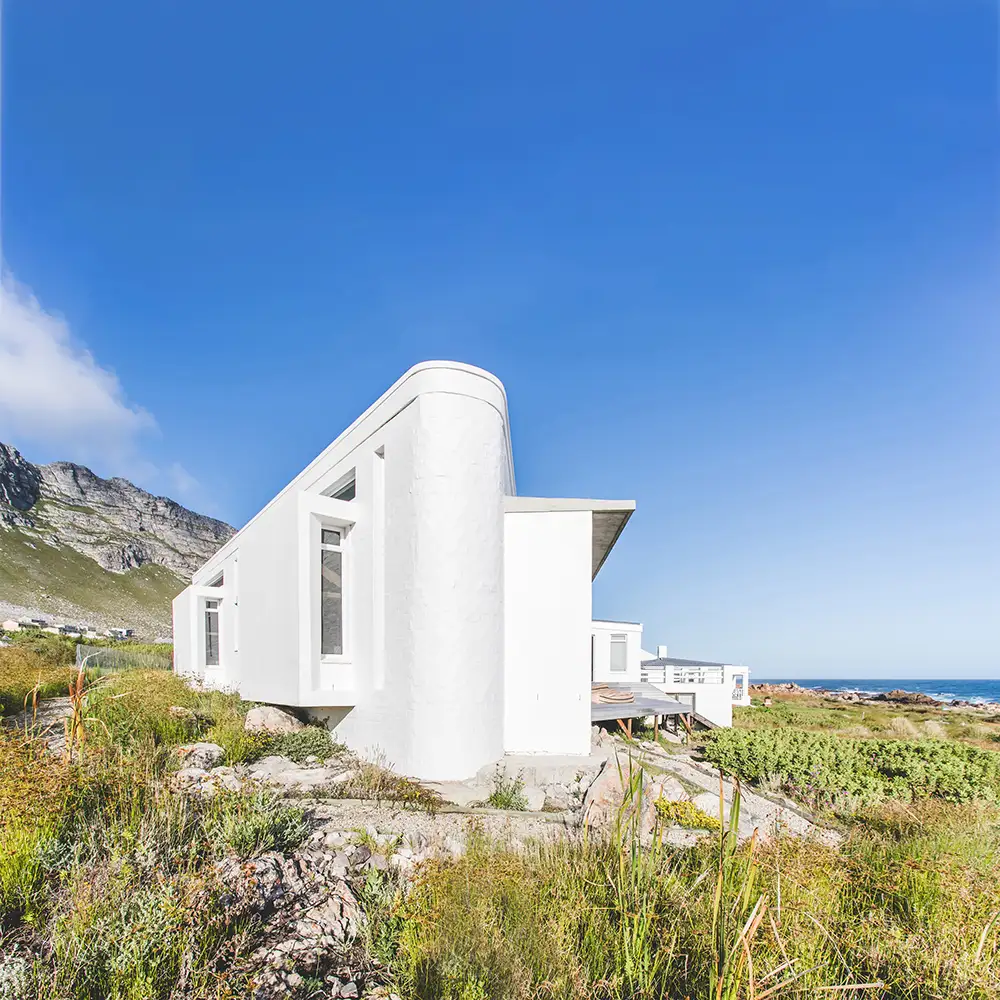 White curved wall of the new addition among fynbos and mountains