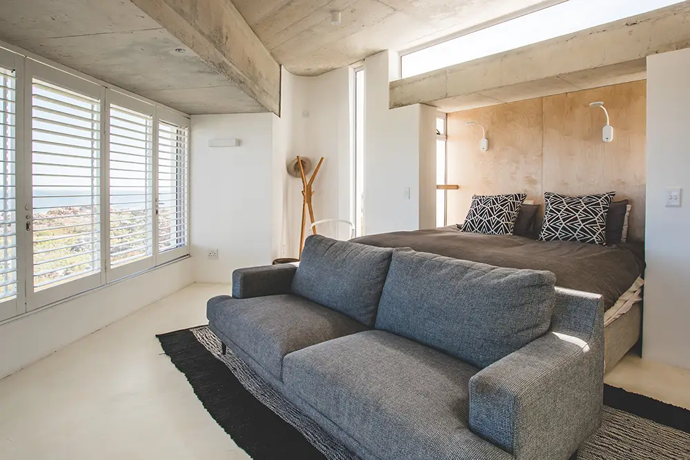 Bedroom and sitting area with shutters and a concrete ceiling