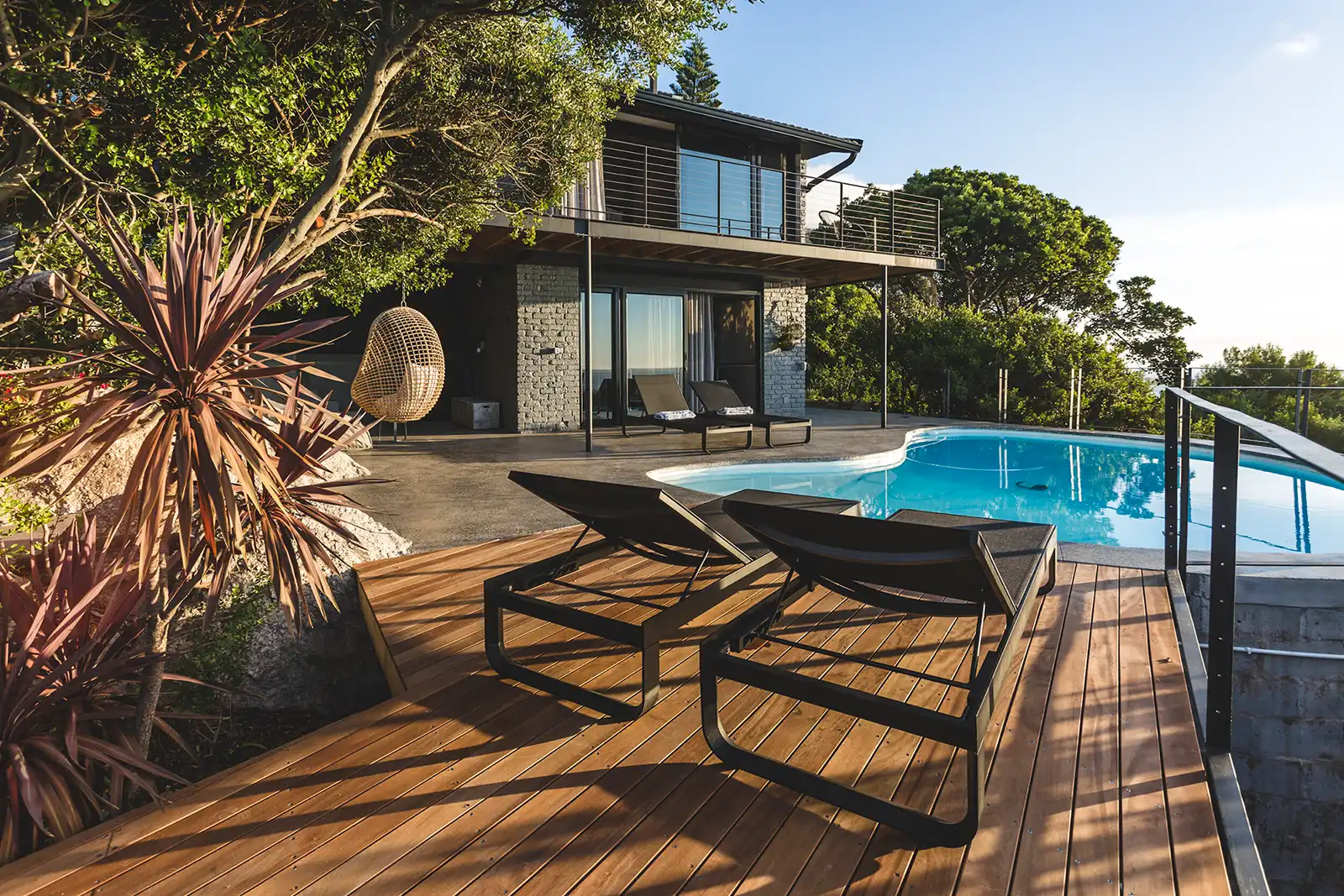 Timber deck with loungers beside the pool and the house