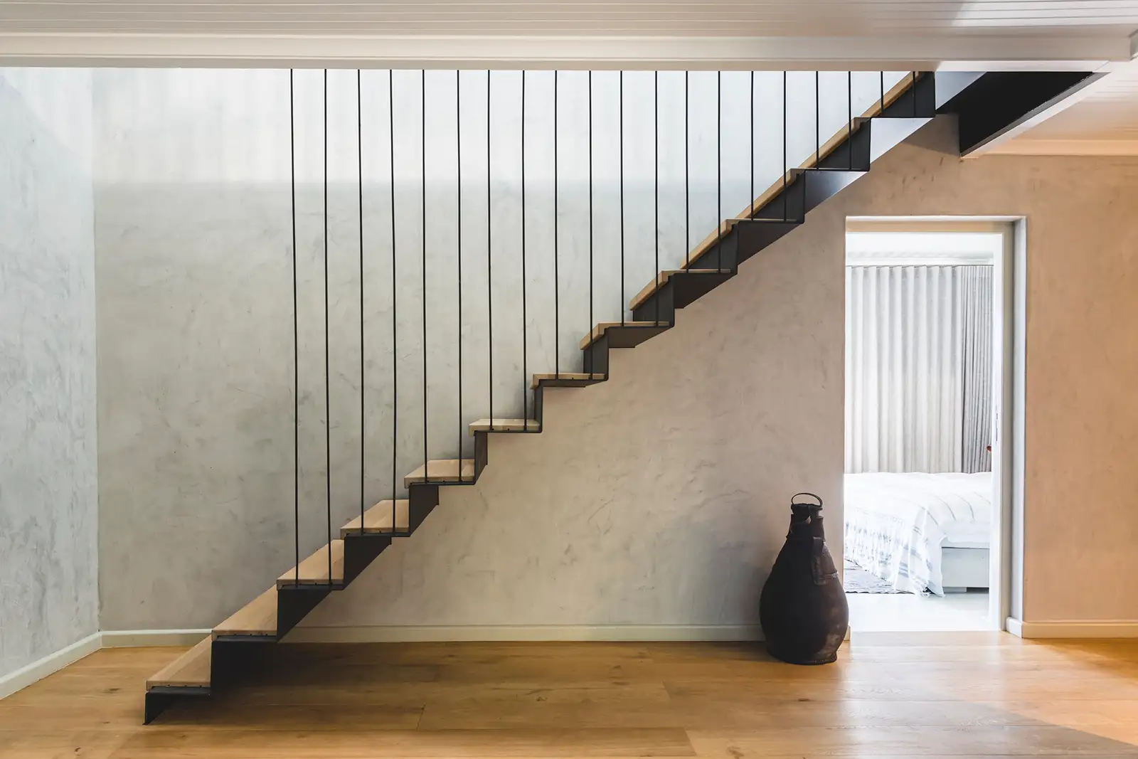 Steel cantilevered stair against a polished plaster wall