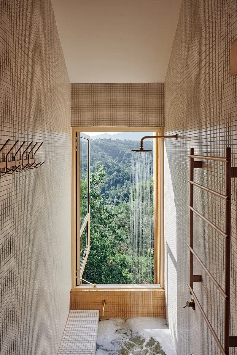 Timber-lined bathroom with a tall window onto the forest