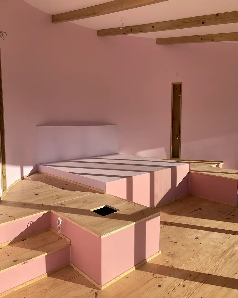 Interior under construction with pink-lined walls and timber steps