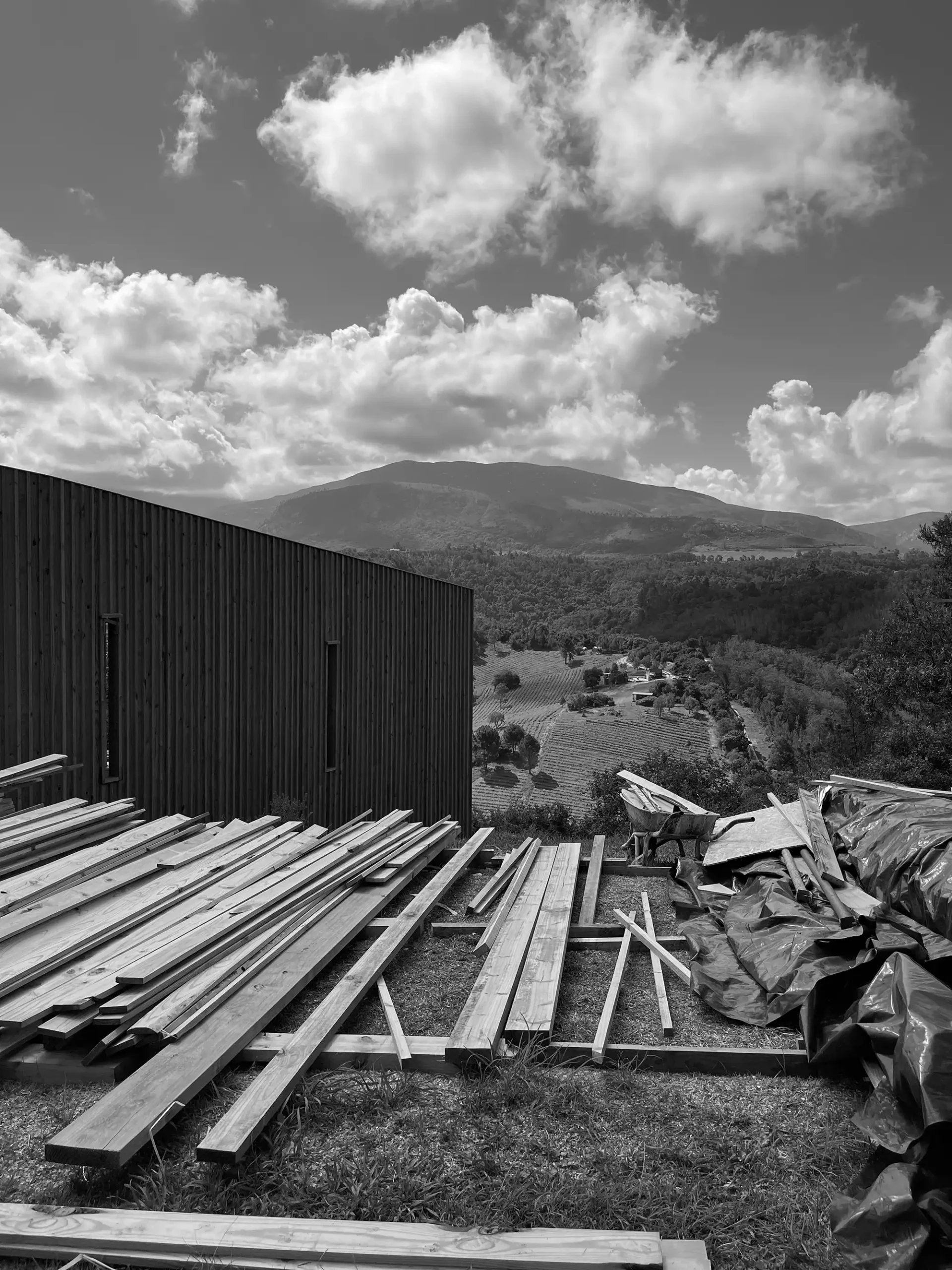Timber stacked on site during construction, with the valley behind