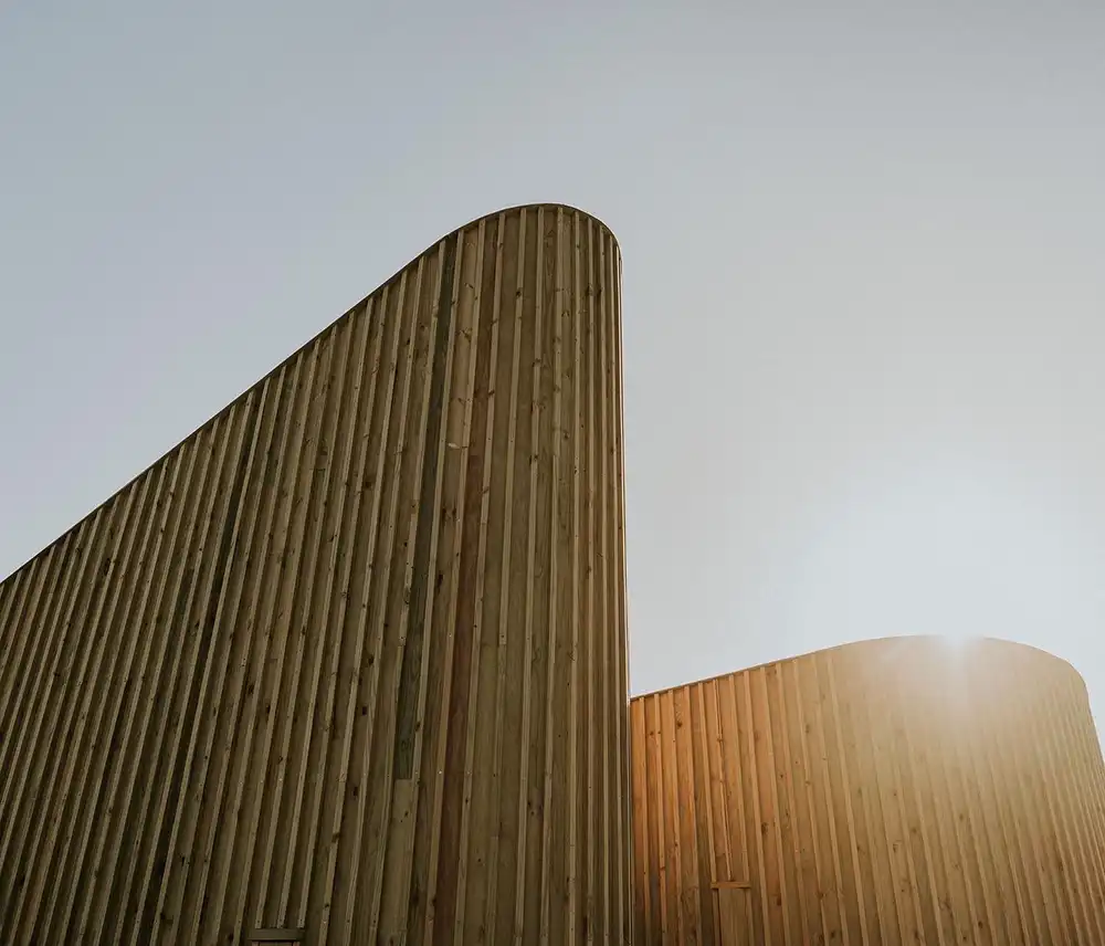 Sun setting behind the curved timber volumes