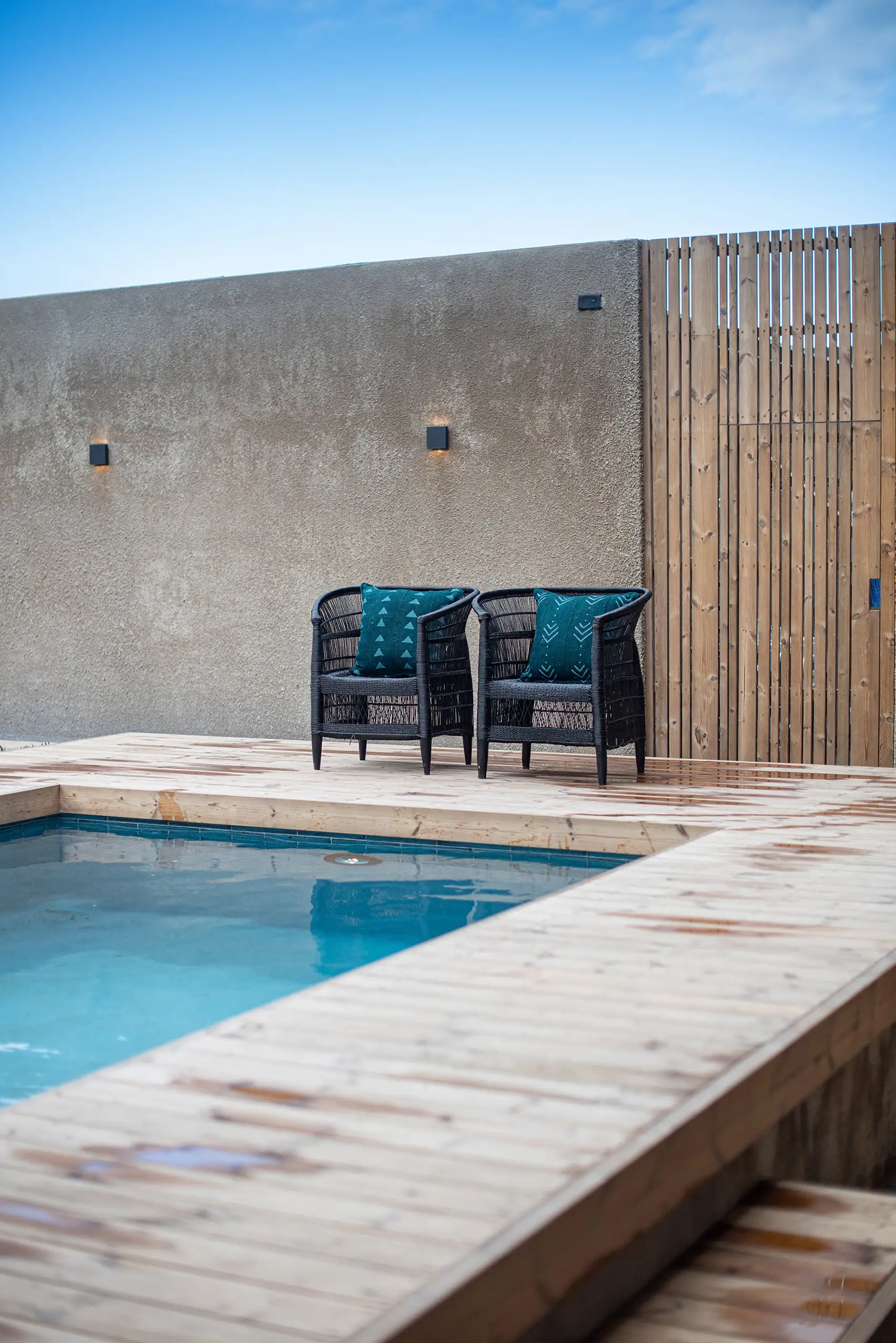 Pool with a timber deck beside a concrete wall
